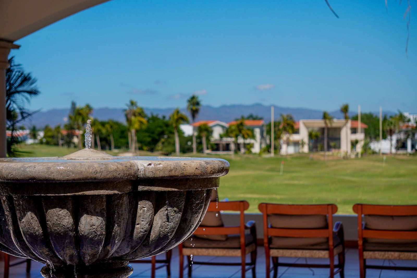 Clubhouse terrace with a wooden pergola and tropical greenery